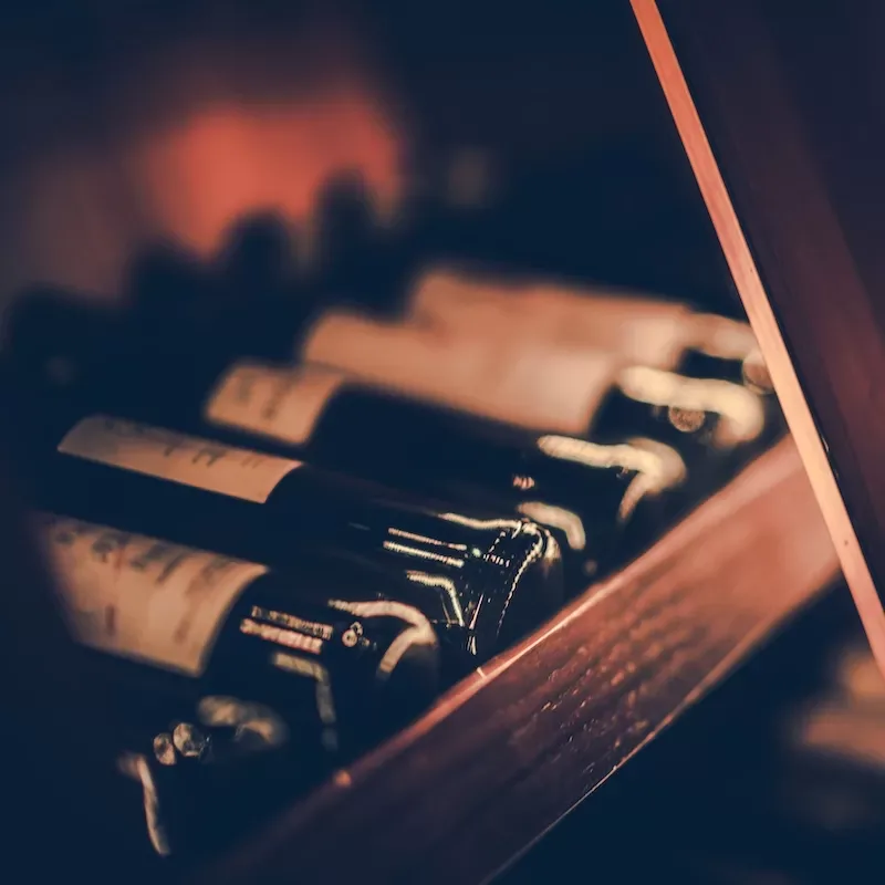 Bottles of Red Wine on the Wooden Shelf. Shallow Depth of Field.