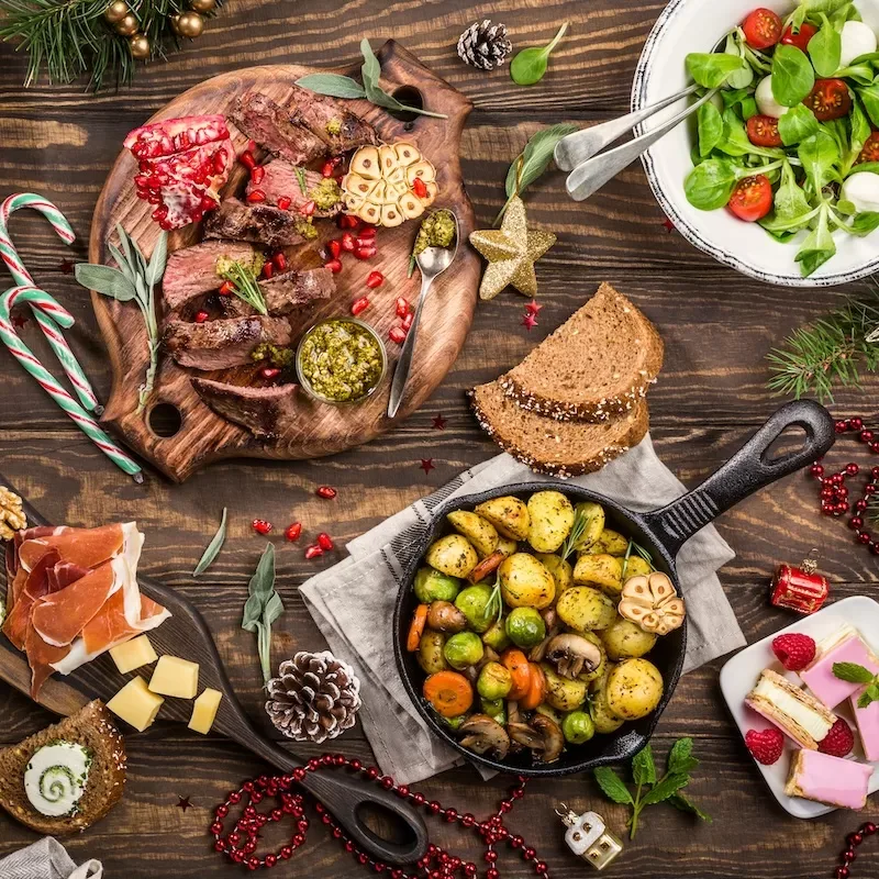 Delicious Christmas themed dinner table with roasted meat steak, appetizers and desserts. Top view. Flat lay with holiday concept.